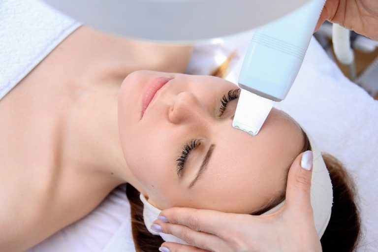 Woman receiving cleansing therapy with a professional ultrasonic equipment in cosmetology office